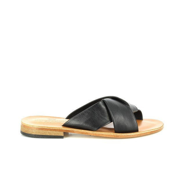 The image showcases a pair of Antichi Romani 905 Nero Black Cross-Strap Slides elegantly displayed on a soft, neutral-toned surface. The slides feature a sleek black leather upper with refined cross-straps that gracefully crisscross over the foot, highlighting the meticulous craftsmanship of the Italian brand. The interior lining is also crafted from luxurious leather, promising both comfort and breathability.