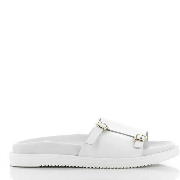The image displays a pair of Antichi Romani 912 Bianco White Slides set against a soft, neutral background. The slides feature a sleek, minimalist design with a smooth white leather upper that highlights the fine Italian craftsmanship. The round toe shape adds a touch of elegance, while the 2cm heel-platform provides a slight lift for added comfort.