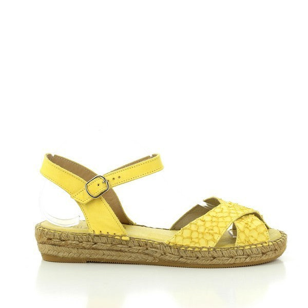 The Calzanor 1538 Yellow Slingback Espadrilles are showcased in a bright, sunny outdoor setting. The vibrant yellow leather upper features a classic slingback design, complemented by a round toe. The eco-friendly jute sole is clearly visible, highlighting the espadrilles' handcrafted quality. The soft, supple leather lining peeks through, enhancing the shoe's overall elegance and comfort.