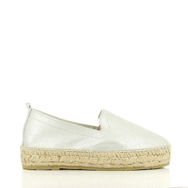 The image showcases a pair of Calzanor 1852 Silver Loafer Espadrilles, elegantly displayed on a neutral background. The espadrilles feature a sleek silver leather upper with a soft sheen that catches the light, highlighting the shoe’s craftsmanship. The hand-stitched detailing around the edges emphasizes its artisanal quality. The natural jute fiber sole is visible, adding a textured contrast to the smooth leather, and a modest 3cm platform gives a slight lift.