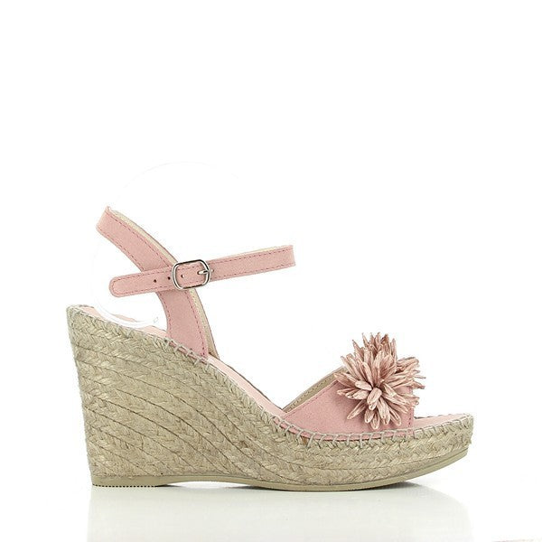 The image captures the Calzanor 2019 Pink Slingback Espadrilles, highlighting their feminine and artisanal details. The soft pink leather upper is adorned with delicate decorative flowers, adding a charming touch. The jute-wrapped 10 cm platform heel gives height, while the slingback strap with buckle fastening ensures a secure fit. The round toe shape complements the classic espadrille design.