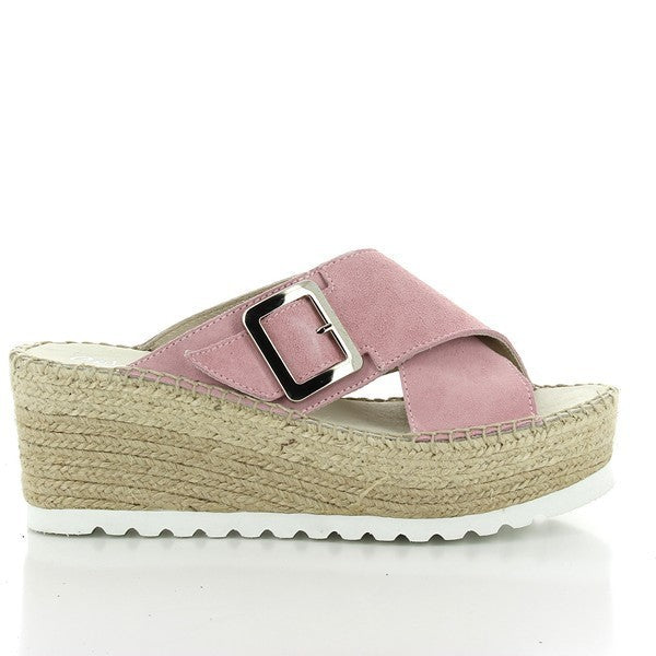 The image showcases the Calzanor 2041 Pink Cross-Strap Slide Espadrilles, beautifully arranged on a light-colored surface. The soft, pastel pink leather straps are crossed over the top, creating an elegant and minimal design. The espadrilles have a natural jute-wrapped platform, highlighting their artisanal craftsmanship. The rounded toe adds to their laid-back, yet stylish appeal, while the raised 7cm platform provides a subtle lift.