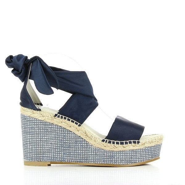 A pair of Calzanor 2137 Navy Lace-Up Espadrilles is displayed on a clean, neutral background. The deep navy leather upper contrasts beautifully with the natural beige jute sole, which features intricate hand-stitching. The lace-up design adds a stylish and functional touch, allowing for an adjustable, secure fit. The 10cm platform creates an elegant lift, while the round toe shape maintains a classic, timeless look.