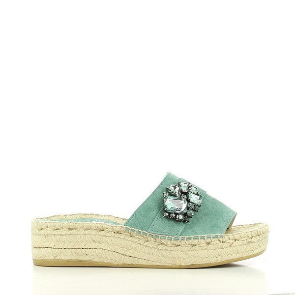 A pair of Calzanor 2142 Turquoise Slide Espadrilles is displayed on a clean, light background. The bright turquoise leather upper pops against the neutral setting, showcasing a smooth finish. The round toe shape maintains a classic appeal, while the eco-friendly jute sole is slightly visible, emphasizing its breathable and flexible qualities. The 4.5cm heel-platform adds a subtle lift, providing both style and comfort. The overall presentation is fresh and inviting, perfect for summer outings.