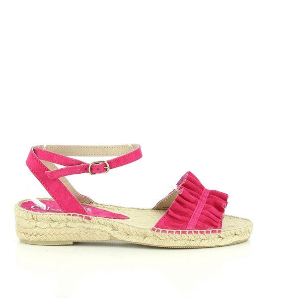 The Calzanor 2237 Alhambra Pink Slingback Espadrilles are showcased in a bright and inviting setting. These stylish women's shoes feature a soft pink leather upper that elegantly complements the light-colored jute sole. The slingback design includes a delicate ankle strap for a secure fit, while the round toe adds a classic touch. The espadrilles are positioned on a wooden surface, surrounded by natural elements like soft greenery and floral accents, emphasizing their casual yet chic aesthetic.