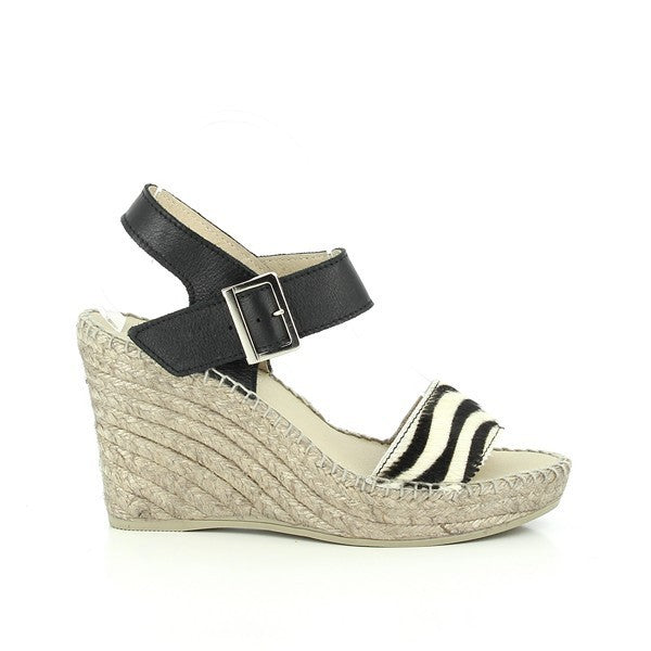 A pair of Calzanor 2238 Black & White Slingback Espadrilles is elegantly displayed against a neutral backdrop. The shoes feature a classic black and white color scheme, with a leather upper and lining that exudes sophistication. The espadrilles showcase a round toe design and a substantial 10cm heel-platform, highlighting their stylish silhouette. The hand-stitched detailing adds a touch of artisanal craftsmanship, while the jute sole peeks out, emphasizing the natural materials used in their creation.