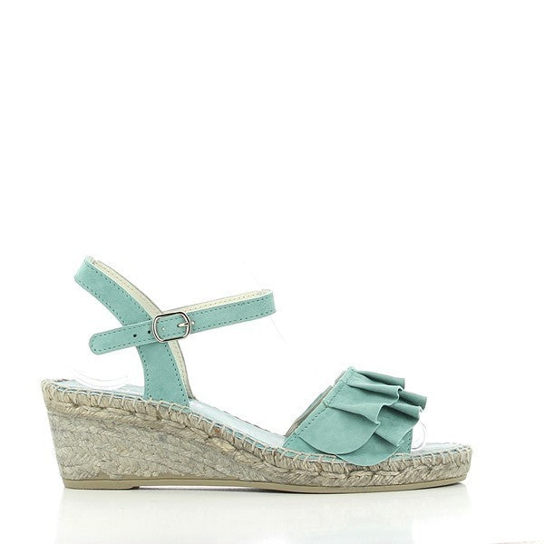 The Calzanor 743 Turquoise Slingback Wedge Espadrilles are showcased in a bright and inviting setting. The espadrilles feature a vibrant turquoise upper made from high-quality leather, which beautifully contrasts with the natural jute sole. The stylish slingback design allows for an adjustable fit, ensuring comfort while providing an elegant touch. The round toe shape and 5.5 cm wedge height enhance the overall silhouette, making them perfect for various occasions.