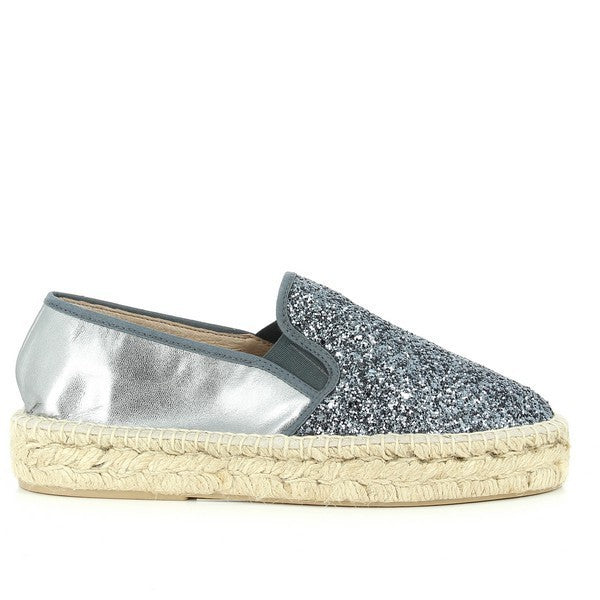 The photo features a pair of Calzanor 95010PO Silver Espadrilles, showcasing a shimmering silver leather upper paired with a natural jute sole. The espadrilles have a round toe shape for a comfortable fit and a soft leather lining. With a 3 cm heel-platform, they offer a subtle lift while maintaining comfort for all-day wear. The eco-friendly jute sole adds durability and flexibility. These stylish espadrilles combine sustainability with elegance, making them a perfect addition to any wardrobe.