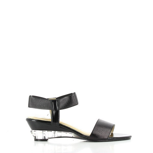 The Dalessi Deluxe Black Slingback Sandals are shown from a side angle, showcasing the sleek black leather upper and the elegant 5.5 cm transparent wedge heel. The elastic slingback strap gently wraps around the heel, ensuring a secure fit, while the soft leather lining provides comfort and breathability. The round toe shape offers a relaxed fit, and the durable synthetic sole is visible, ensuring traction and stability.