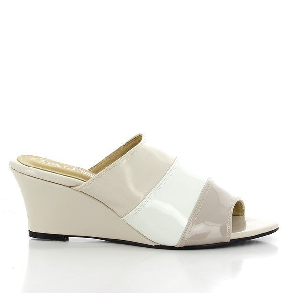 The Dalessi Deora Beige Slides are shown from the side, highlighting the wide strap design in beige synthetic material. The 6.5 cm wedge heel adds a touch of height while maintaining comfort and stability.