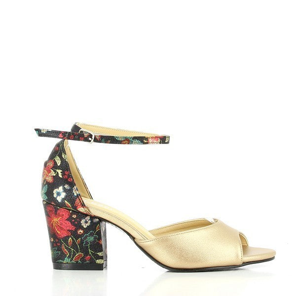 The Dalessi Deuce Gold Floral Slingback Sandals showcase a luxurious gold leather upper adorned with intricate black floral motifs. The sandals feature a peep toe design, offering a chic, breathable look. The black heel contrasts beautifully with the gold, while the adjustable slingback strap ensures a secure fit. The 7 cm heel adds a flattering lift, and the round toe shape provides comfort for all-day wear. The overall design combines elegance with modern flair, perfect for various occasions.