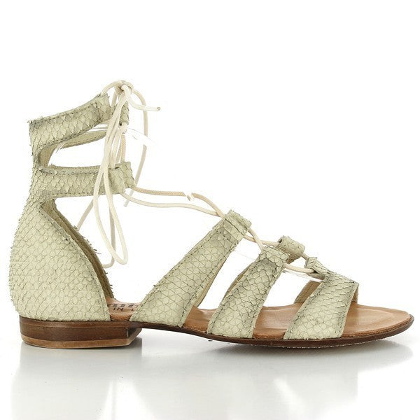 A clear shot of the side of the sandal, showcasing its sleek beige leather upper. The soft, minimalist design with the thin straps elegantly frames the foot.