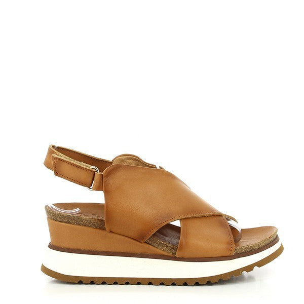 The Felmini B706 Tan Slingback Sandals feature a sleek and elegant profile with crisscross leather straps that wrap around the foot, offering a secure and stylish fit. The wedge heel adds a modern touch to the classic design, providing both comfort and height.