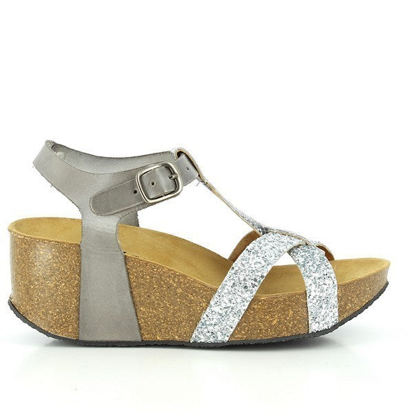 A close-up of Plakton's 273015 Silver Wedges, showcasing the sleek profile and craftsmanship. The silver leather upper contrasts elegantly with the cork sole, highlighting the adjustable buckle strap and cross-band design for a secure fit and stylish appeal.