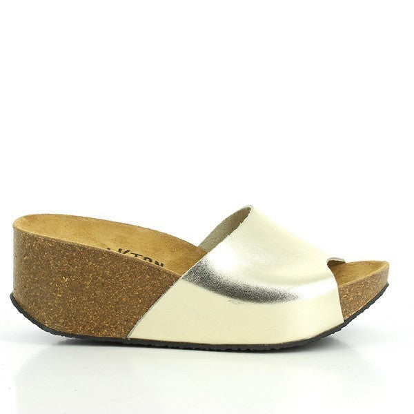 A chic photo showcasing Plakton's 273036 Gold Wedges from their Women's Collection. Crafted in Spain, these wedges feature a premium leather upper, adjustable ankle strap, and a comfortable cork sole. Perfect for elevating any casual outfit with their elegant design and superior comfort.