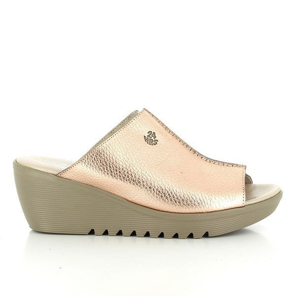 The 24 Hrs 23285 Metallic Pink Wedges are showcased against a neutral background. The wedges feature a shimmering metallic pink leather upper, adding a touch of elegance. The sleek 6 cm heel-platform offers a sophisticated lift, while the round toe shape ensures timeless style. The craftsmanship highlights the high-quality leather lining and synthetic sole, underscoring the luxurious and comfortable design typical of Spanish-made footwear.