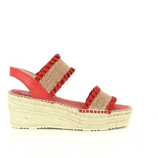 The image features a pair of Calzanor 2245 Paris Red Slingback Espadrilles, elegantly displayed on a light wooden surface. The espadrilles are crafted from vibrant red fabric with a glossy finish, showcasing their stylish slingback design. The soft leather lining is subtly visible at the opening, indicating comfort and quality. A round toe completes the design, while the 7 cm heel-platform adds a touch of sophistication. 