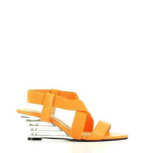 The Dalessi Delussi Orange Slingback Sandals are shown from the side, featuring a vibrant orange leather upper and a unique 7 cm transparent wedge heel. The elastic slingback strap wraps comfortably around the heel, providing both style and security. The soft leather lining is slightly visible along the inner edges, ensuring comfort. The round toe shape offers a relaxed fit, and the durable synthetic sole supports everyday wear. 