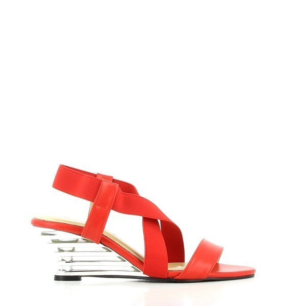 The Dalessi Delussi Red Slingback Sandals are shown from a side angle, highlighting the vibrant red leather upper and the elegant 7 cm transparent wedge heel. The elastic slingback strap fits comfortably around the heel, offering a secure and stylish look. The soft leather lining is visible along the edges, ensuring breathability and comfort. The round toe shape adds a relaxed, natural fit, while the synthetic sole is designed for durability and traction. 