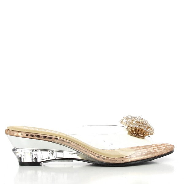 A sleek side view of the Dalessi Dualism Rose Gold Slide, showcasing the transparent upper with its delicate decorative flower and the subtle 2.5 cm heel-platform in a soft rose gold finish.