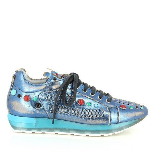 A close-up of the Forte 8260 Metallic Blue Sneakers, showcasing the sleek leather upper with a metallic blue finish, adorned with vibrant red, black, turquoise blue, and green studs. The braided leather detail on the side adds texture, while the clean, rounded toe offers a classic silhouette.